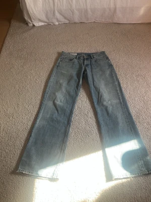 Vintageblå raka low waist jeans från Zara - Säljer ett par vintageblå jeans från Zara i low waist storlek 38. Jeansen har rak passform med klassisk femficksdesign. Tillverkade i denim med snygg tvättad look och subtila slitningar. Perfekta till en avslappnad och trendig stil.