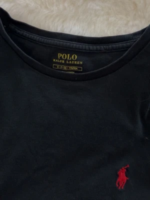 Tshirt Polo Ralph Lauren - En svart T-shirt med röd logga från polo Ralph lauren. Den är i storlek S och passar säkert både tjej och kille! Jättefint skick och knappt använd