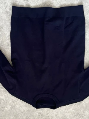 Sayless Mörkblå stickad tröja - En stilren mörkblå stickad tröja med rund halsringning och långa ärmar. Tröjan har ribbade muddar vid hals, ärmslut och nederkant. Perfekt basplagg för garderoben och enkel att matcha med olika outfits.