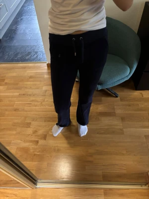 Mörkblå mjukisbyxor  - Säljer ett par mörkblå mjukisbyxor från Juicy couture. Byxorna har fickor fram och två bakfickor med knappar. Materialet är skönt. Det saknas en metallgrej på ena snöret, annars är de i väldigt bra skick. 