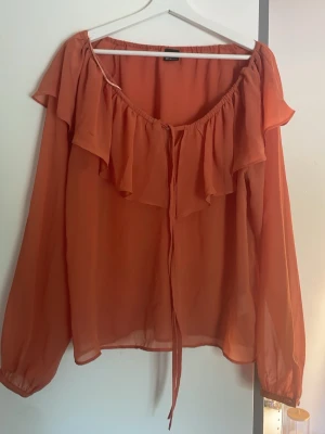 blus med volang Gina Tricot - Säljer en snygg rblus från Gina Tricot i storlek 36. Blusen har långa ärmar, volangdetalj längs ringningen och knytband framtill. Tillverkad i ett tunt, lätt och transparent tyg som ger en luftig känsla. Går att bära off shoulder!!