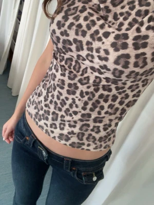 Leopardmönstrad topp med kort ärm - Säljer en snygg leopardmönstrad topp med korta ärmar och mjukt, stretchigt material. Toppen har en figurnära passform och en lätt draperad halsringning. Använd 1 gång pågrund att jag inte gillar den så mycket!