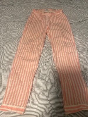 Randiga pyjamasbyxor från Lexington - Säljer ett par pyjamasbyxor från Lexington. Byxorna har rosa och vita vertikala ränder, elastisk midja och raka ben. Perfekta för mysiga kvällar hemma eller när du vill chilla i stil.