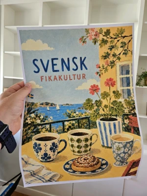 Poster fika A3 - Säljer en färgglad poster med motiv av svensk fikakultur. Affischen visar tre kaffekoppar med olika mönster, en kanelbulle på fat, blommor i kruka och havsutsikt med segelbåtar. Texten 'SVENSK FIKAKULTUR' står i blått och rött mot en ljus bakgrund.