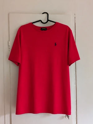 Ralph Lauren t-shirt❤️ - Klassisk röd T-shirt från Polo Ralph Lauren med den ikoniska broderade ponnyloggan i mörkbltt på bröstet. Stilren modell som passar perfekt till jeans, shorts eller under en overshirt. Fint skick och en snygg baströja som funkar året runt. 📏 Storlek: Xl (18-20) men passar storlek S i vuxenstorlek! ✨ Skick: Mycket bra men den är lite nopprig! 📦 Kan skickas snabbt! Skriv gärna vid frågor eller om du vill ha fler bilder/mått 😊