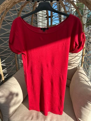 Lång t-shirt/miniklänning strl. 34/36 - Röd kortklänning/t-shirt från Joelle by Byblos med rund halsringning och puffiga kortärmar. Tillverkad i ett mjukt material som känns bekvämt mot huden. Perfekt för dig som vill ha en enkel men stilren look.