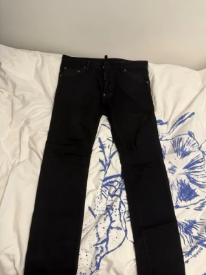 Svarta  jeans från Dsquared2 - Säljer ett par svarta  jeans från Dsquared2. Jeansen har klassisk femficksdesign, smal passform och bälteshällor. Materialet är stretchigt och bekvämt, perfekt för dig som gillar en cool look.