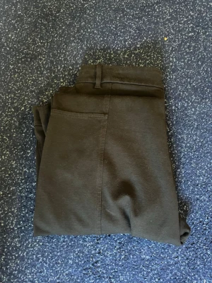Svarta slim chinos - Säljer ett par svarta chinos med slim fit och hög midja. Byxorna har bälteshällor och raka ben. Materialet är mjukt och stretchigt, vilket gör dem riktigt bekväma. Perfekta till en avslappnad look eller när du vill vara lite mer uppklädd.