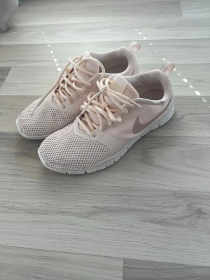 Nike träningsskor, Nike rosa skor - Snygga ljusrosa Nike skor med vit sula och mesh-överdel som ger bra ventilation. Skorna har klassisk snörning och en sportig look. Perfekta för dig som gillar stilrena och bekväma skor till vardags. Diskret logga på sidan och dragflik bak. 