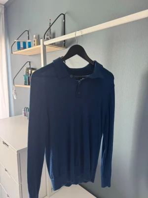 Mörkblå stickad tröja Brothers - En stilren mörkblå stickad tröja från brothers med lång ärm och klassisk krage med två knappar. Tröjan har ribbade muddar vid ärmslut och nederkant. Pris kan diskuteras vid snabb affär.