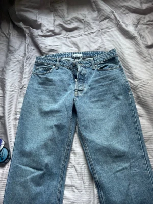 Blå raka jeans med hög midja - Säljer ett par klassiska blå jeans med rak passform och hög midja. Jeansen har fem fickor, bälteshällor och knappgylf. Materialet är kraftig denim i 100% bomull. Perfekta för en avslappnad och tidlös stil.