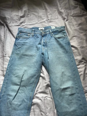Ljusblå relaxed jeans från Jack & Jones - Säljer ett par ljusblå relaxed fit jeans från Jack & Jones, modell Chris. Klassisk femficksdesign, raka ben och knappgylf. Perfekta för en chill och avslappnad stil. Tillverkade i slitstarkt denimtyg.