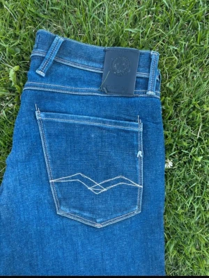 Raplay anbass jeans - Snygga blå slim fit jeans med klassisk femficksdesign och kontrastsömmar på bakfickan. Jeansen har en mörk tvätt och raka ben. Materialet är denim, vilket ger en skön och slitstark känsla. Perfekta till en avslappnad stil.