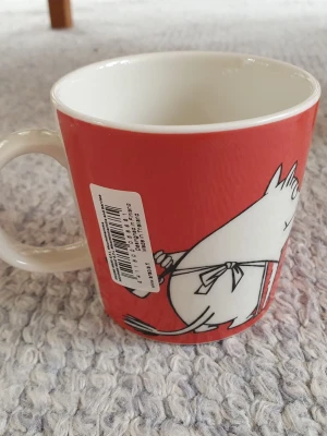 Muminmugg Muminmamma Mumin  - Oanvänd mugg med etikett som fått ett nagg i nedre kanten, se bilder. Säljer fler Muminmuggar så kika gärna på mina övriga annonser också. Packar mycket noggrant. 