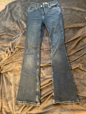 Blå bootcut jeans från Perfect Jeans - Säljer ett par klassiska blå bootcut jeans från Perfect Jeans. Jeansen har fem fickor, normalhög midja och snygga kontrastsömmar. Tillverkade i denim med en lätt stretch för skön passform. Perfekta för dig som gillar en tidlös och avslappnad look.