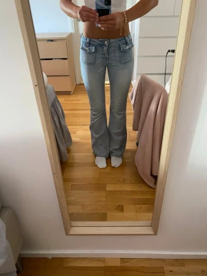 Ljusblå bootcut jeans med låg midja - Säljer ett par ljusblå bootcut jeans med låg midja och framfickor med lock. Det är uppsydda längst ner och Jag är 170 cm lång💖