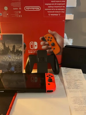 Nintendo Switch med röda Joy-Con - Nintendo Switch spelkonsol, helt nytt (kvitto från Elgiganten finns) Hogwarts legacy och L.A noire medföljer har endast haft den i 1 månad och spelat 2 gånger allt medföljer🙏