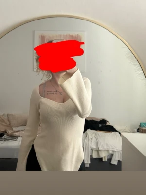 Ljusbeige ribbad stickad tröja - Trendig ljusbeige stickad tröja med djup v-ringning och långa, vida ärmar. Tröjan är ribbstickad och har en figurnära passform som framhäver siluetten. Perfekt för dig som gillar minimalistisk och stilren look.