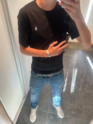 Ralph lauren T-shirt - Säljer en svart t-shirt med liten vit logga på bröstet. Klassisk passform och rund halsringning. Perfekt basic-plagg som funkar till allt och är enkel att matcha. Materialet känns mjukt och skönt mot huden.
