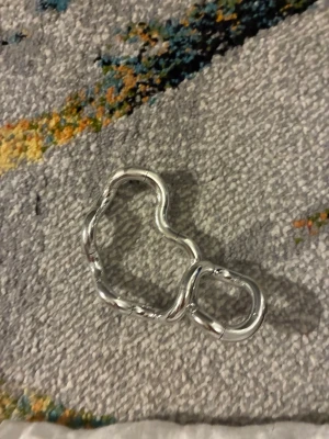 Silvrig Tangle  - Säljer ett silvrig Tangle, vågiga länkar i metall. Länkarna är ovala och har en cool, organisk form. Hjälper att hålla händerna sysselsatta.