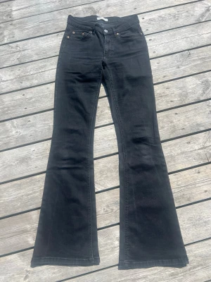 Svarta bootcut jeans från Perfect Jeans/Gina Tricot - Säljer ett par svarta bootcut jeans från Perfect Jeans/Gina Tricot i storlek 34. Jeansen har klassisk femficksdesign, hög midja och utsvängda ben. Materialet är stretchigt denim som sitter snyggt och bekvämt. Perfekta för dig som gillar en retroinspirerad look.