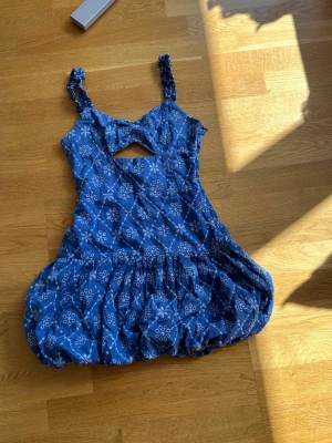  Trendig Blå kort klänning med mönster - Söt blå kortklänning med vita blommönster och ballongformad kjol. Klänningen har breda axelband, en liten cut-out framtill och voluminös nederdel. Perfekt för sommarens varma dagar och har en ungdomlig vibe.