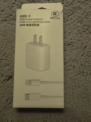 USB-C iPhone laddare - Säljer en vit USB-C 20W strömadapter med tillhörande USB-C till Lightning-kabel. Perfekt för att ladda din iPhone eller annan kompatibel enhet snabbt och smidigt. Kompakt design i plast och passar i vägguttag med två stift.