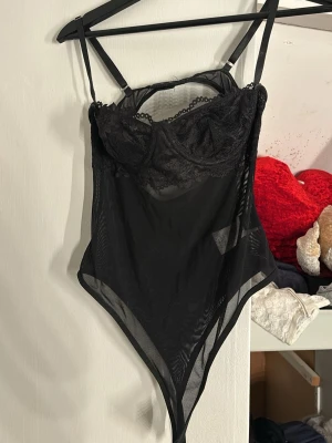 Svart spets body  - En svar body med spets vid brösten och ett genomskinligt tyg på resterande. Perfekt till fest eller för att spicea upp en outfit. Endast använd 1 gång 🤗
