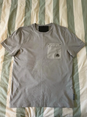 Moose Knuckles T-shirt  - Helt oanvänd Moose Knuckles t-shirt i grå/beige färg storlek s. Rfid tagg finns