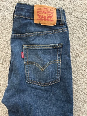 Levi's 512 blå jeans, ungdom storlek 164 - Säljer ett par klassiska blå Levi's 512 jeans med rak passform och  avsmalnande ben. Slim taper. Logga bak sitter inte fast helt, se bilder