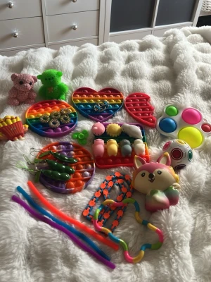 Stort paket med fidgetleksaker - Säljer ett färgglatt paket med olika fidgetleksaker, bland annat pop it i hjärt- och cirkelform, squishies, stretchy ormar, piprensare, stressbollar och små mjuka djur. Perfekt för dig som gillar att pilla och ha något att göra med händerna. Är otroligt gammla men i jättebra skick, vill bara bli av med så pris går att diskutera