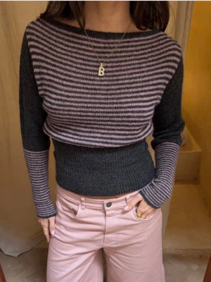 Randig stickad tröja i grått och rosa - Säljer en snygg stickad tröja med smala ränder i rosa och mörkgrått. Perfekt till höst och vinter för en trendig look. Helt ny med prislappen kvar! Säljer då den inte passade mig, annars superfin kvalité och allt 