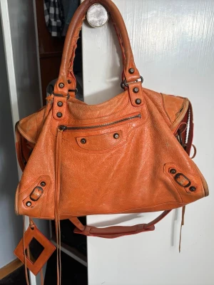 Orange balenciaga city bag - Säljer min älskade balenciaga väska. Helt okej skick lite sliten. Litet hål finns men det är igensytt så det blir inte större (se sista bilden). 