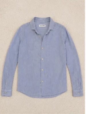 Blårandig skjorta från Jack & Jones - Snygg blårandig skjorta från Jack & Jones med klassisk krage och knappar framtill. Skjortan har långa ärmar och är tillverkad i ett lätt och luftigt bomullstyg, perfekt för en stilren look.