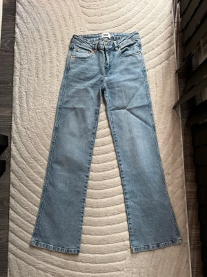Bootcut jeans i ljusblå denim Lager157 - Snygga bootcut jeans i ljusblå denim från Lager 157. Klassisk femficksmodell med hög midja och vida ben. Perfekta för dig som gillar 90-talsvibbar och avslappnad stil. Tillverkade i slitstarkt bomullsmaterial.