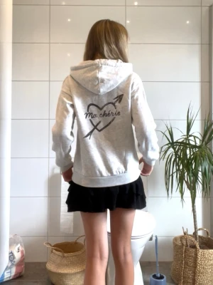 Grå hoodie med tryck 'Ma chérie' - Snygg ljusgrå hoodie med huva och trycket 'Ma chérie'. Hoodien har ribbade muddar och en avslappnad passform. 