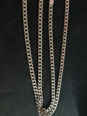 Kedjehalsband i silverfärgad metall - Snyggt halsband med kraftig kedja i silverfärgad metall. Klassisk design med platta, tätt länkade kedjor och karbinlås. Perfekt för dig som gillar stilrena accessoarer med lite edge. 50 cm långt halsband. Pris kan diskuteras vid snabb affär.