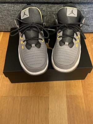 Gråa Air Jordan sneakers med gula detaljer - Snygga gråa Air Jordan sneakers med svarta och gula detaljer. Skorna har perforerad tå, svart mesh på plösen och gula öljetter för skosnörena. Klassisk Jumpman-logga på plösen och vit sula. Perfekta för dig som vill sticka ut med stil. Skorna har bara en liten repa se bild 5💕💕 pris kan diskuteras💕💕orginal box finns med! Orginal pris 1100