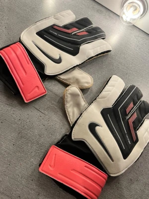 Nike målvaktshandskar  - Säljer ett par Nike målvaktshandskar i svart och blått med vita detaljer. Handskarna har kardborreband vid handleden .  Vid frågor skriv.