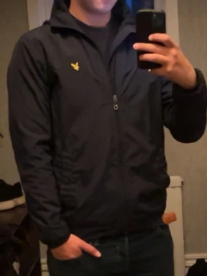 Mörkblå Windbreaker lyle and scott - Snygg mörkblå Windbreaker Lyle and scott, i väldigt bra skick. Skriv om det är något ni undrar över, skriv om ni vill ha bilder på jackan. Kan tvätta innan jag skickar den!😊