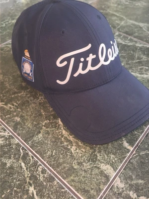 Keps - En clean keps från Titleist. Färg mörkblå och vit. Skicket är mycket bra. Finns en logga på höger sida där det står Real Club Golf Campoamor. Hör av dig vid fler frågor eller bilder!