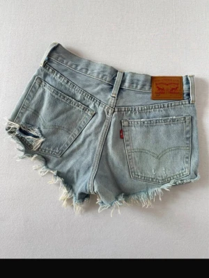Ljusblå Levi's jeansshorts med fransar - Säljer ett par ljusblå jeansshorts från Levi's, super  snygga Perfekta för sommaren och ger en avslappnad vibe.