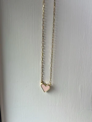 Guldhalsband med hjärthänge - Snyggt halsband i guldton med ett hjärthänge. Hänget är rosa på ena sidan och har texten 'forever' ingraverat på andra sidan. Kedjan har rektangulära länkar som ger ett modernt intryck. Perfekt accessoar för att lyfta din outfit. Orginal pris 7€, säljder för 20kr