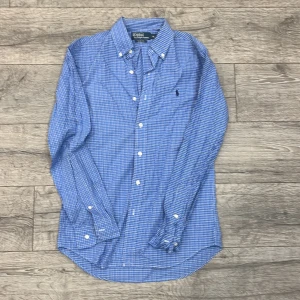 Blå rutig skjorta från Polo Ralph Lauren - Säljer en snygg blå rutig skjorta från Polo Ralph Lauren i storlek M. Skjortan har en slim fit passform och är långärmad med klassiska knappar. Perfekt för både vardag och fest! 💙| Stolek M | Skick 8,5/10 | Hör gärna av dig vid fler frågor! 😊