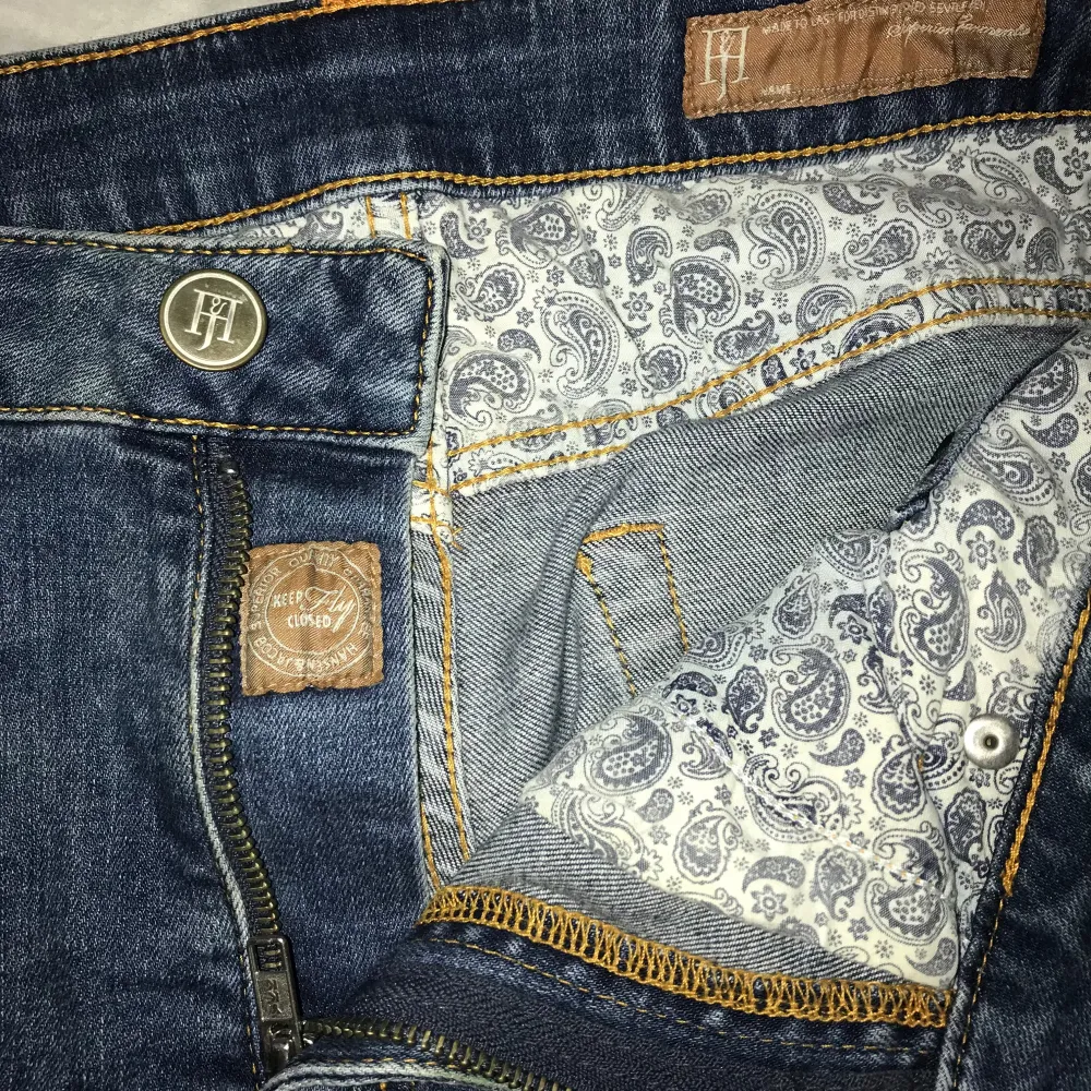 Säljer ett par snygga blå jeans från HANSEN & JACOB i bra skick. De har en klassisk old money stil med en snygg logga på myntfickan och baksidan. Jeansen har en dragkedja och knapp framtill, även riktig snygg design på insidan. Perfekta för både vardag och fest!. Jeans & Byxor.