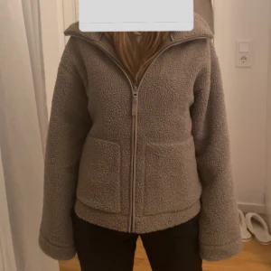 Teddyjacka från H&M - Mysig teddyjacka i färgen beige / brun från H&M i storlek M. Perfekt för höst och vinter med dragkedja framtill och två praktiska fickor. Jackan har en normal passform och är långärmad. Jackan är i mycket bra skick då den använts 2 gånger. Inga fläckar / skador mm. Säljer då den inte kommer till användning. Köpt nyligen och kvitto finns kvar.