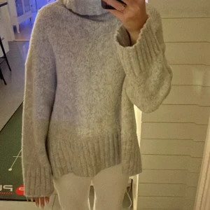 Grå stickad polotröja  - Mysig grå stickad polotröja från H&M i storlek S. Perfekt för kyliga dagar med sin höga krage och långa ärmar. Tröjan har en ribbad kant vid ärmslut och nederkant som ger en snygg detalj. Passar både till vardags och mysiga hemmakvällar💕💕