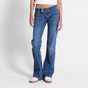 Blå bootcut jeans - Säljer ett par snygga blå bootcut jeans i mycket bra skick. De är lågmidjade med dubbla knappar och har en klassisk femficksdesign. Perfekta för både vardag och fest! 🕺