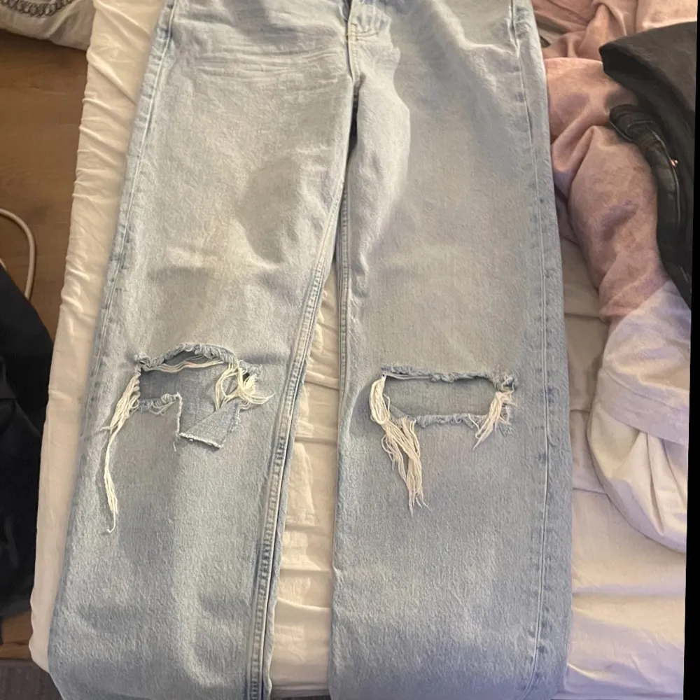 Säljer ett par ljusa jeans i bra skick med coola slitningar på knäna. Perfekta för en avslappnad stil. De har en klassisk femficksdesign och är i en straight passform. . Jeans & Byxor.