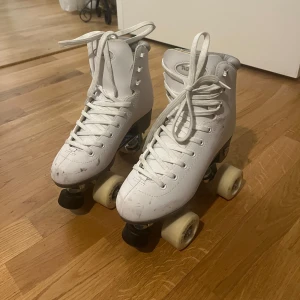 Vita rullskridskor  - Säljer ett par klassiska vita rullskridskor mycket bra skick. De har snörning och är perfekta för både nybörjare och proffs. Storlek 38.